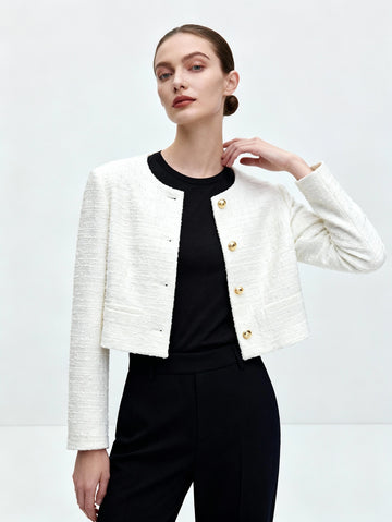 Woman wearing a white textured jacket over a black top and pants on a light gray background