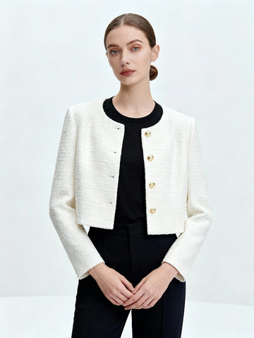 Woman wearing a white textured jacket over a black top and pants on a light gray background