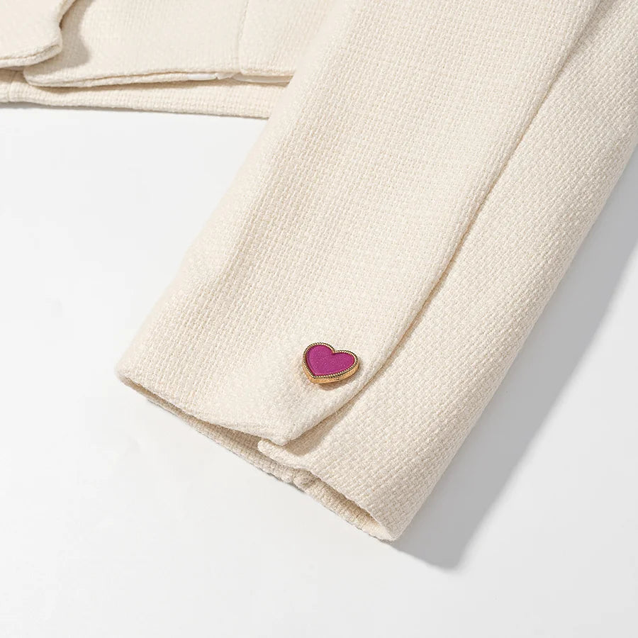 Beige fabric with a heart-shaped cufflink on a light gray background