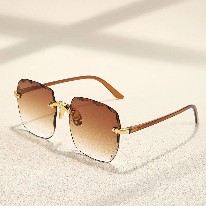 Sunglasses with gold frame and Classic Gradient Glow Shades brown gradient lenses on a light beige background