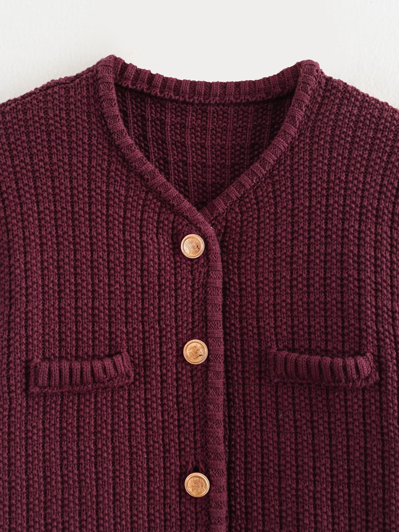 Close-up of a burgundy knitted cardigan with buttons on a white background