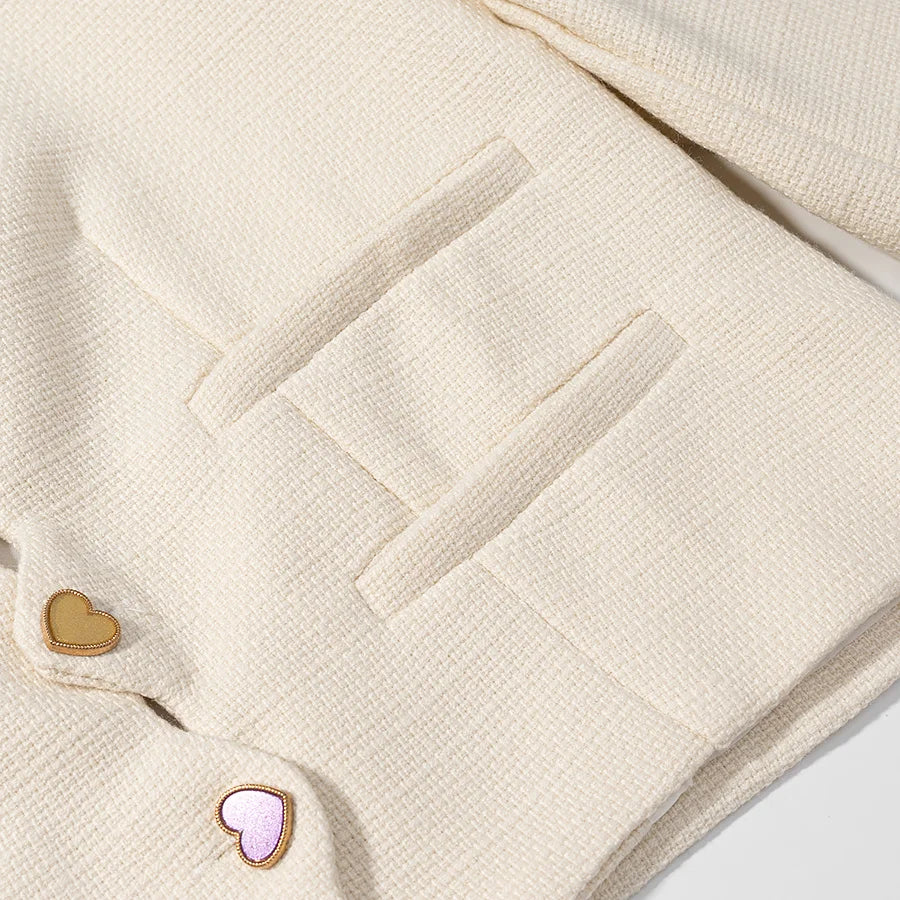 Close-up of a cream-colored textured fabric with heart-shaped buttons on a light gray background