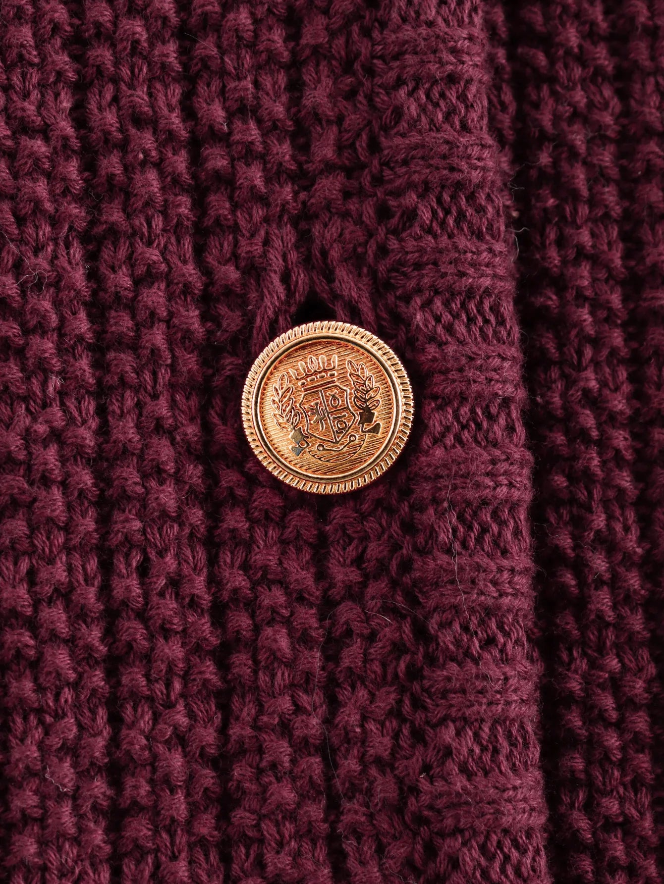 Close-up of a gold button on a textured purple fabric