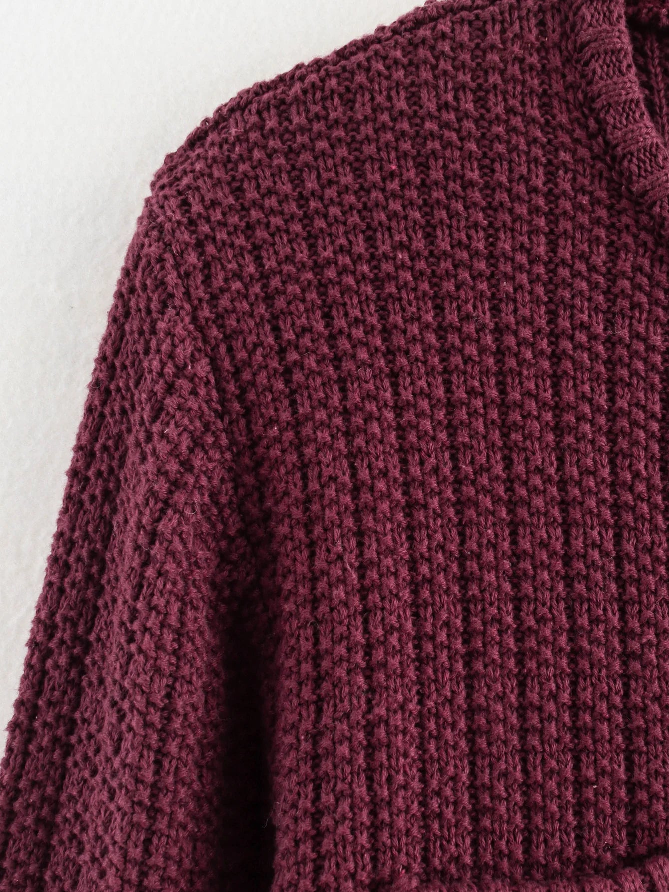 Close-up of a maroon knitted sweater on a light background