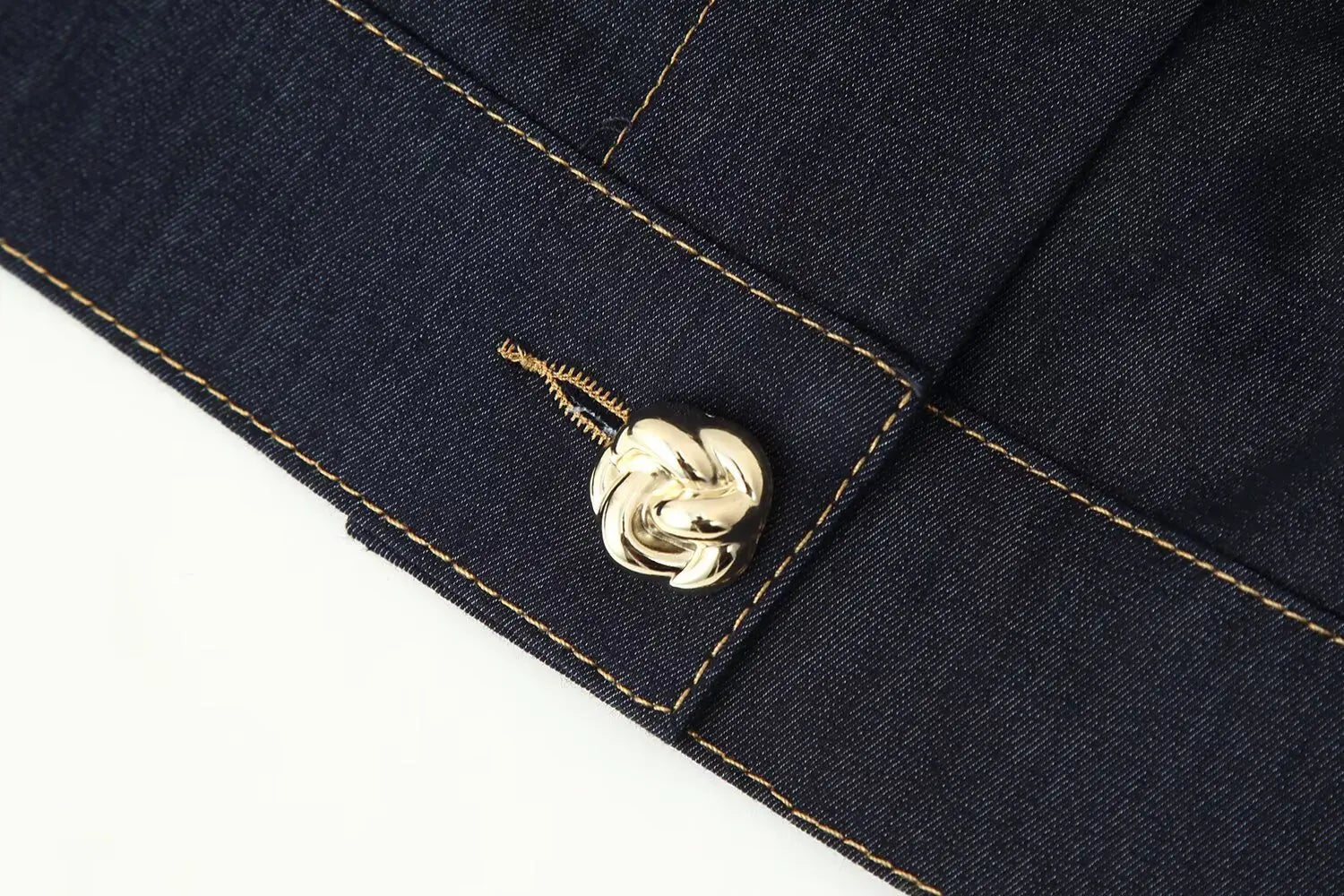Close-up of a navy blue fabric with a gold button and visible brand logo.