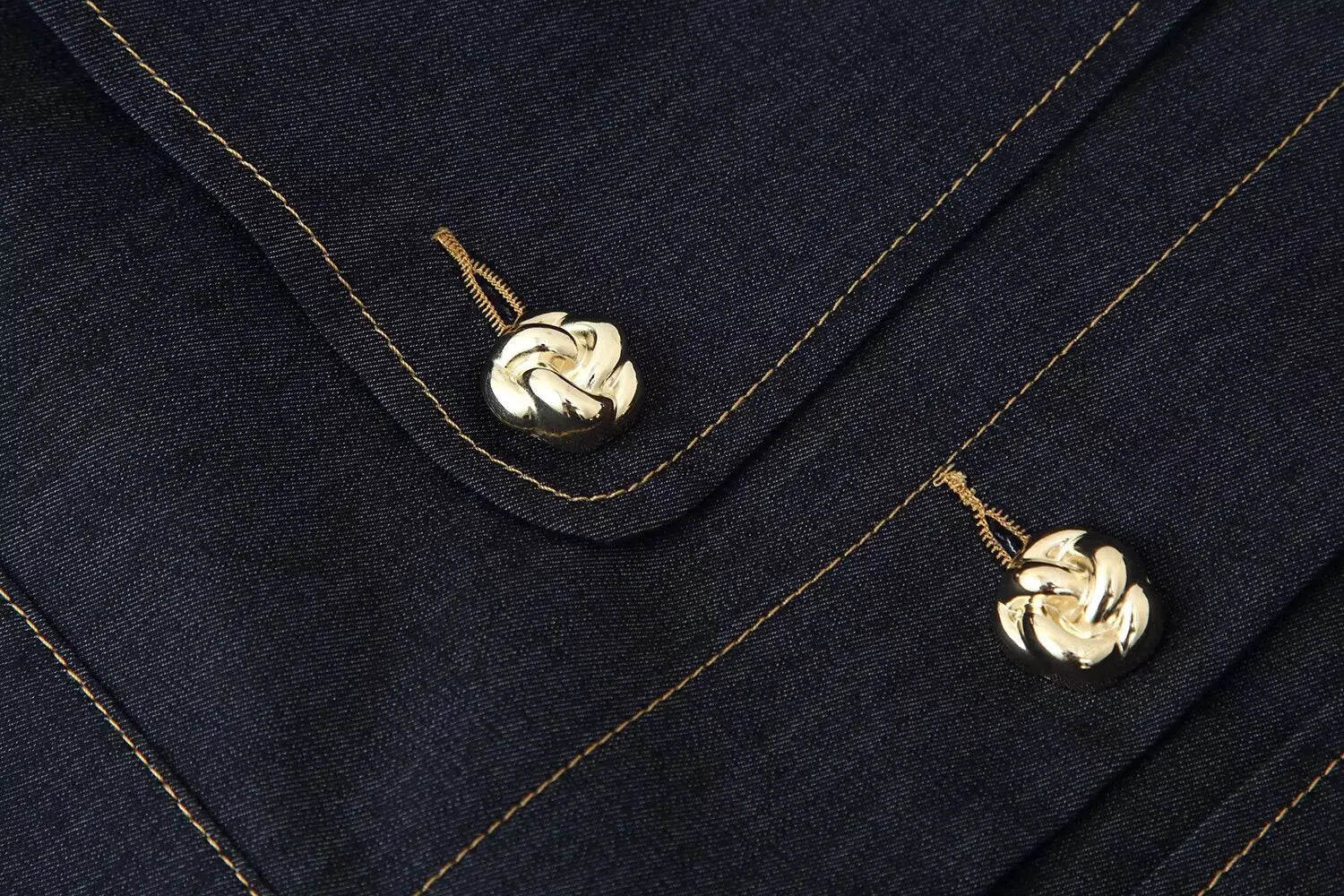 Close-up of a navy blue fabric with gold buttons and stitching