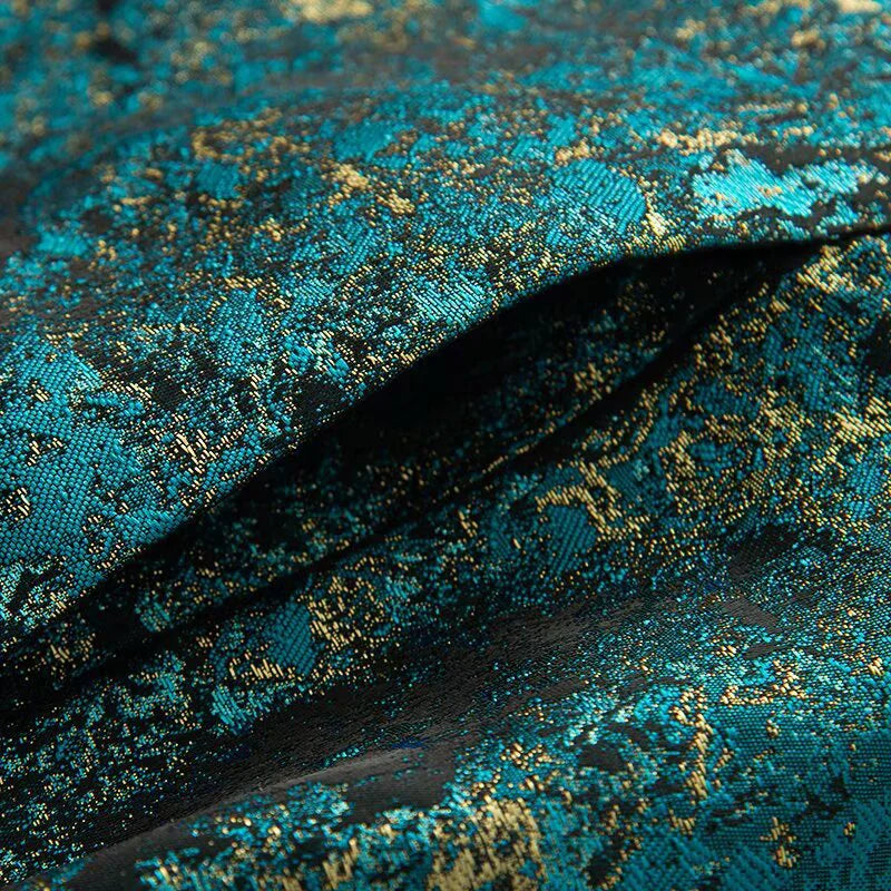 Close-up of blue and gold patterned fabric with a feather