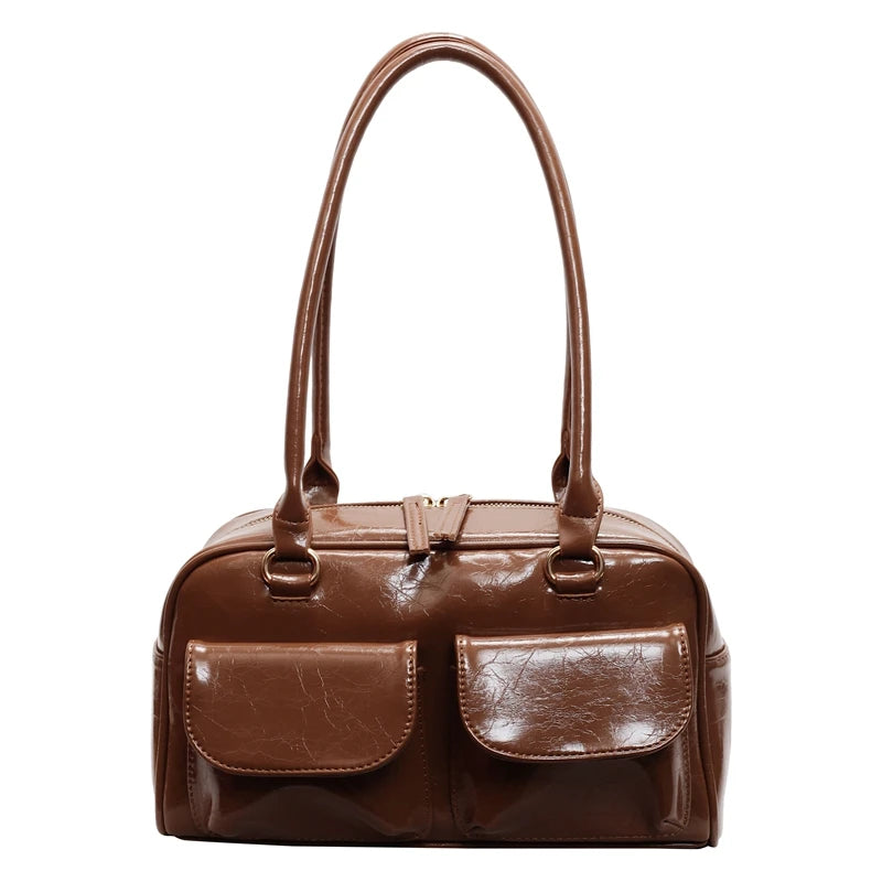 Brown leather handbag with two front pockets on a white background