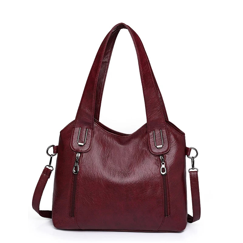 Maroon handbag with silver zippers on a white background