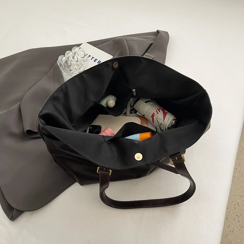 Black bag with a gray garment and items inside on a light surface