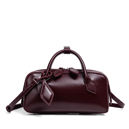 Maroon handbag with bow detail on a white background