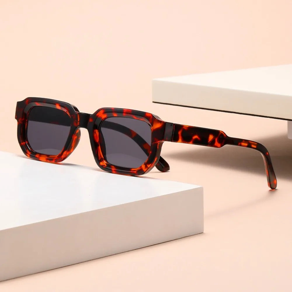 Sunglasses with tortoiseshellLeopard Punk Square Shades lenses on a beige surface