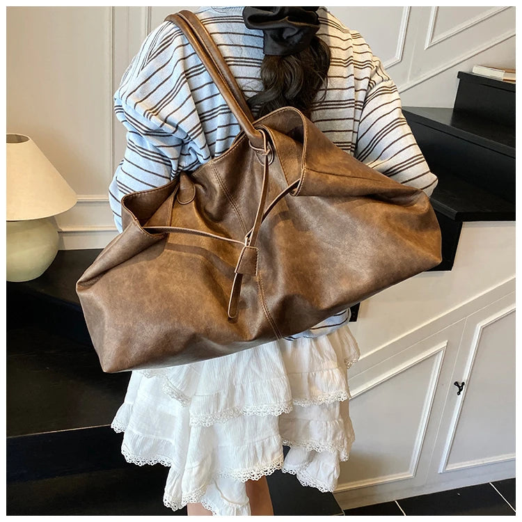 Person holding a Trendy Large Fashion Tote in a room with a lamp and cabinet.