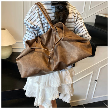 Person holding a Trendy Large Fashion Tote in a room with a lamp and cabinet.