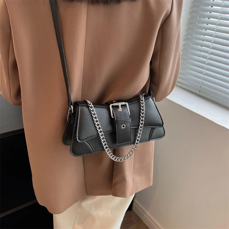 Person wearing a brown coat with a black handbag featuring a chain detail.