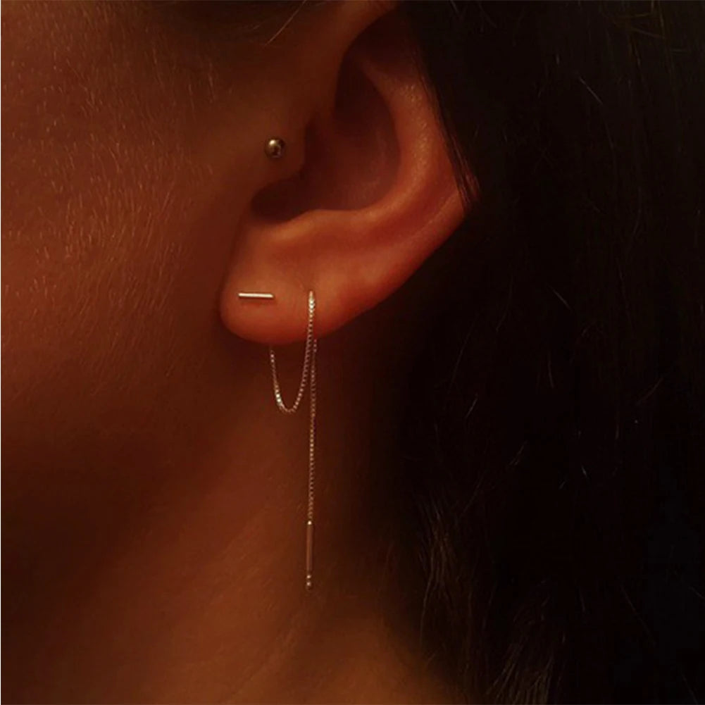 Silver Minimalist Tassel Earrings. Close-up of an ear with a gold bar earring.