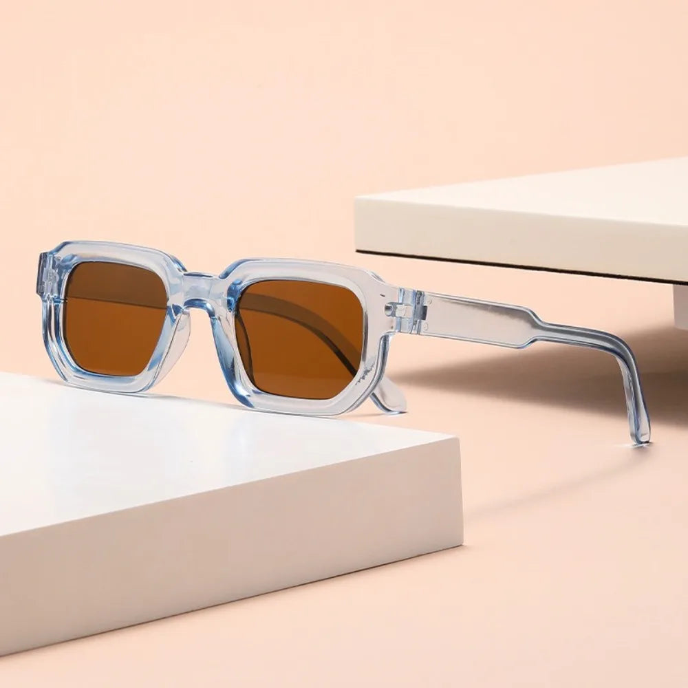Sunglasses with clear blue frame Leopard Punk Square Shades on a beige surface