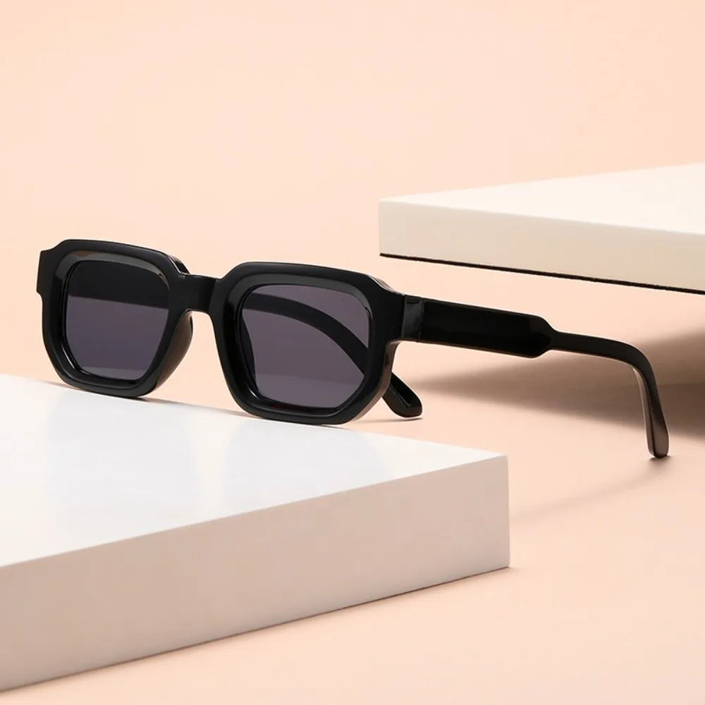Black sunglasses on a beige surface with Leopard Punk Square Shades box in the background