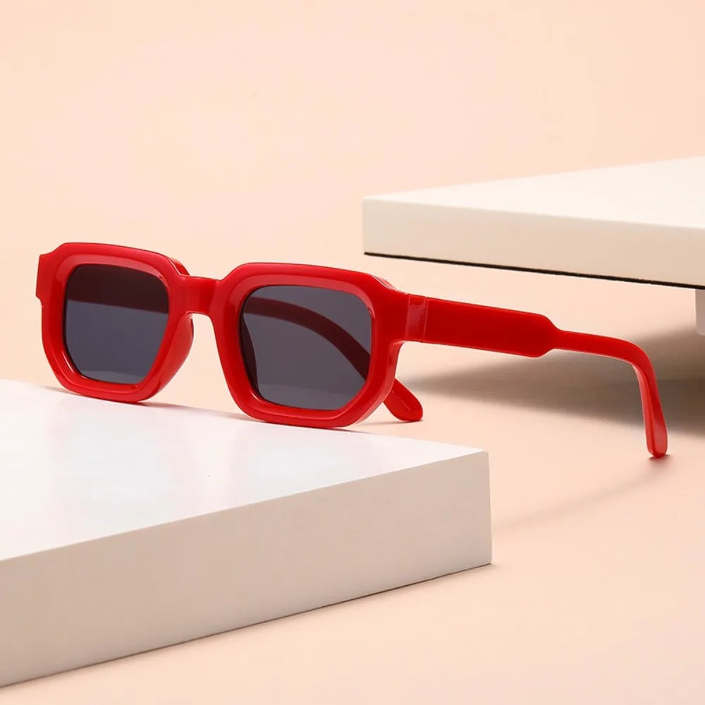 Red sunglasses with dark lLeopard Punk Square Shades on  beige surface