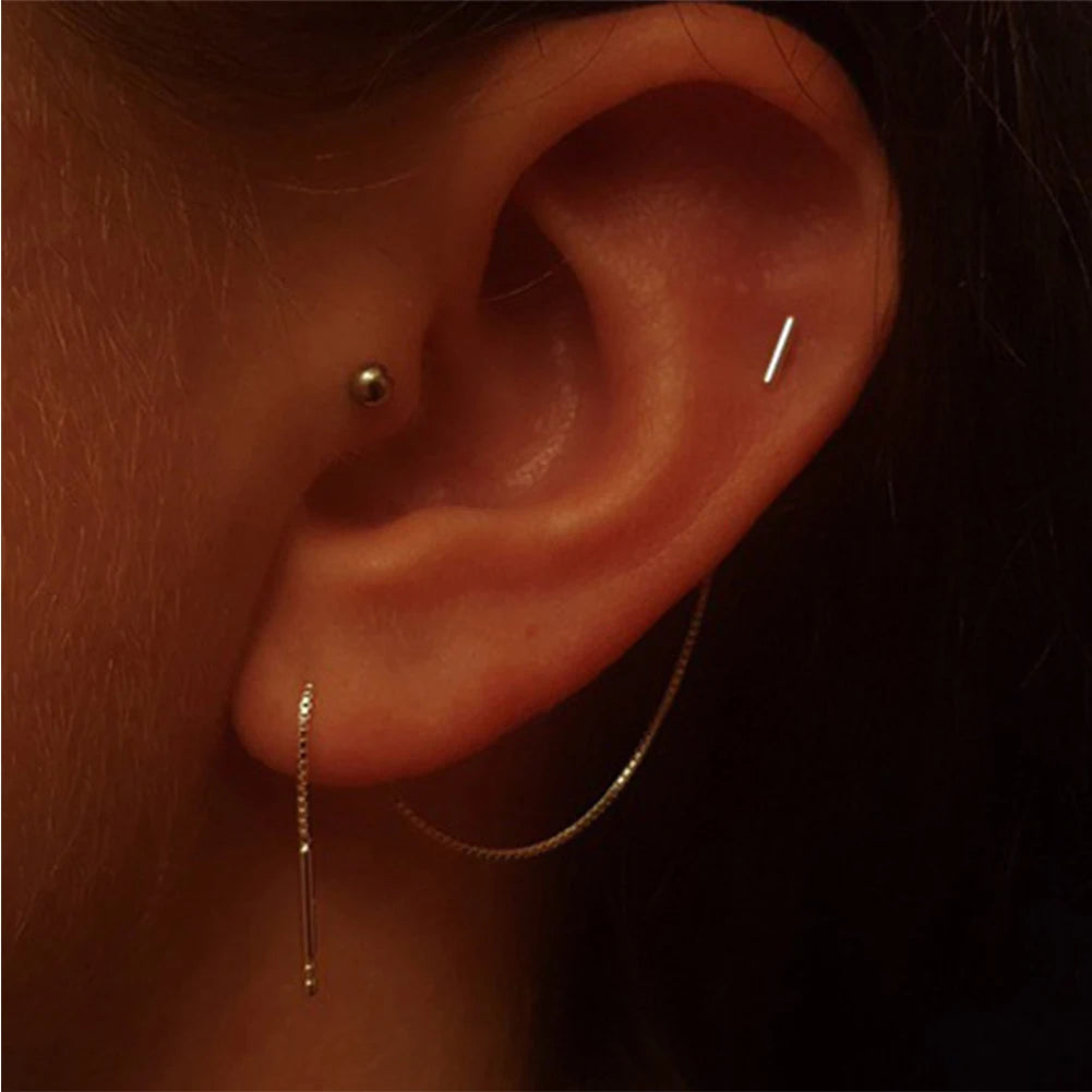 Close-up of an ear with multiple earrings on a dark background with Silver Minimalist Tassel Earrings