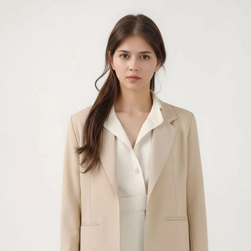 Woman wearing a beige blazer over a white top and pants on a white background