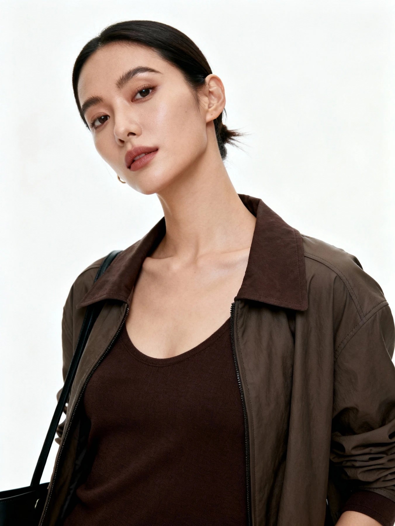 Woman wearing a brown jacket over a black top on a white background