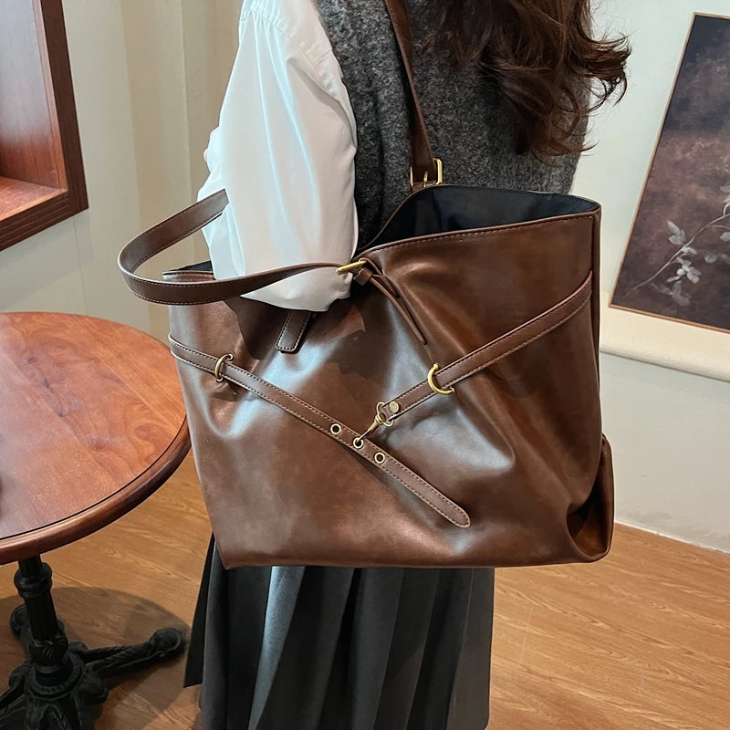 Brown leather bag held by a person in an indoor setting